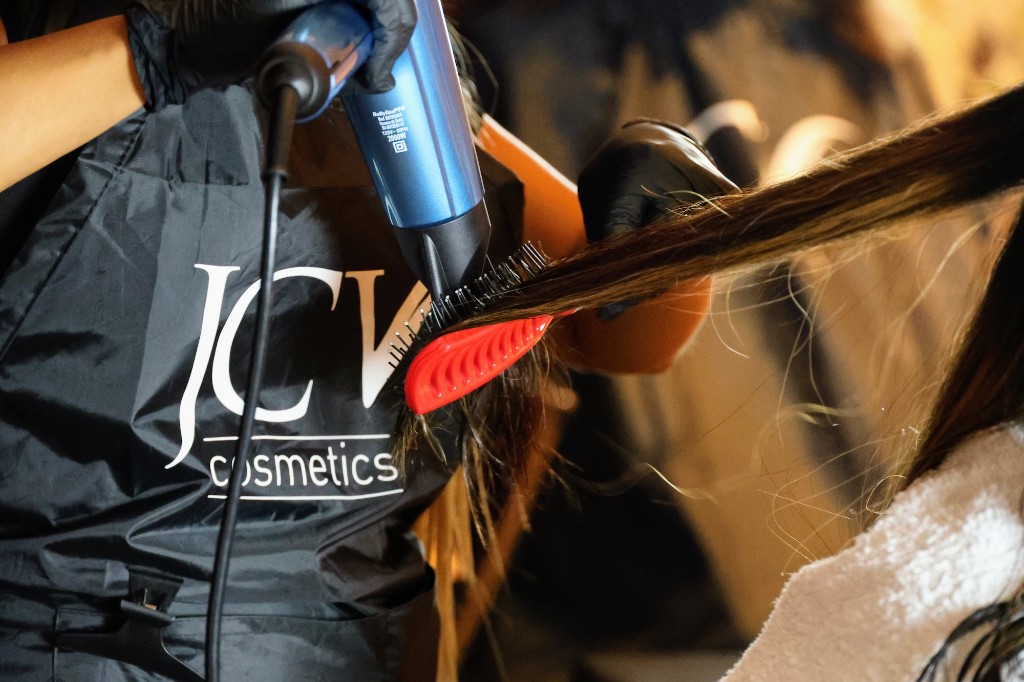 Estilista profesional con delantal JCV Cosmetics trabajando el cabello en salón